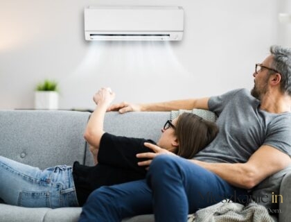 Klimatyzacja w bloku — para odpoczywająca na kanapie pod jednostką wewnętrzną klimatyzatora